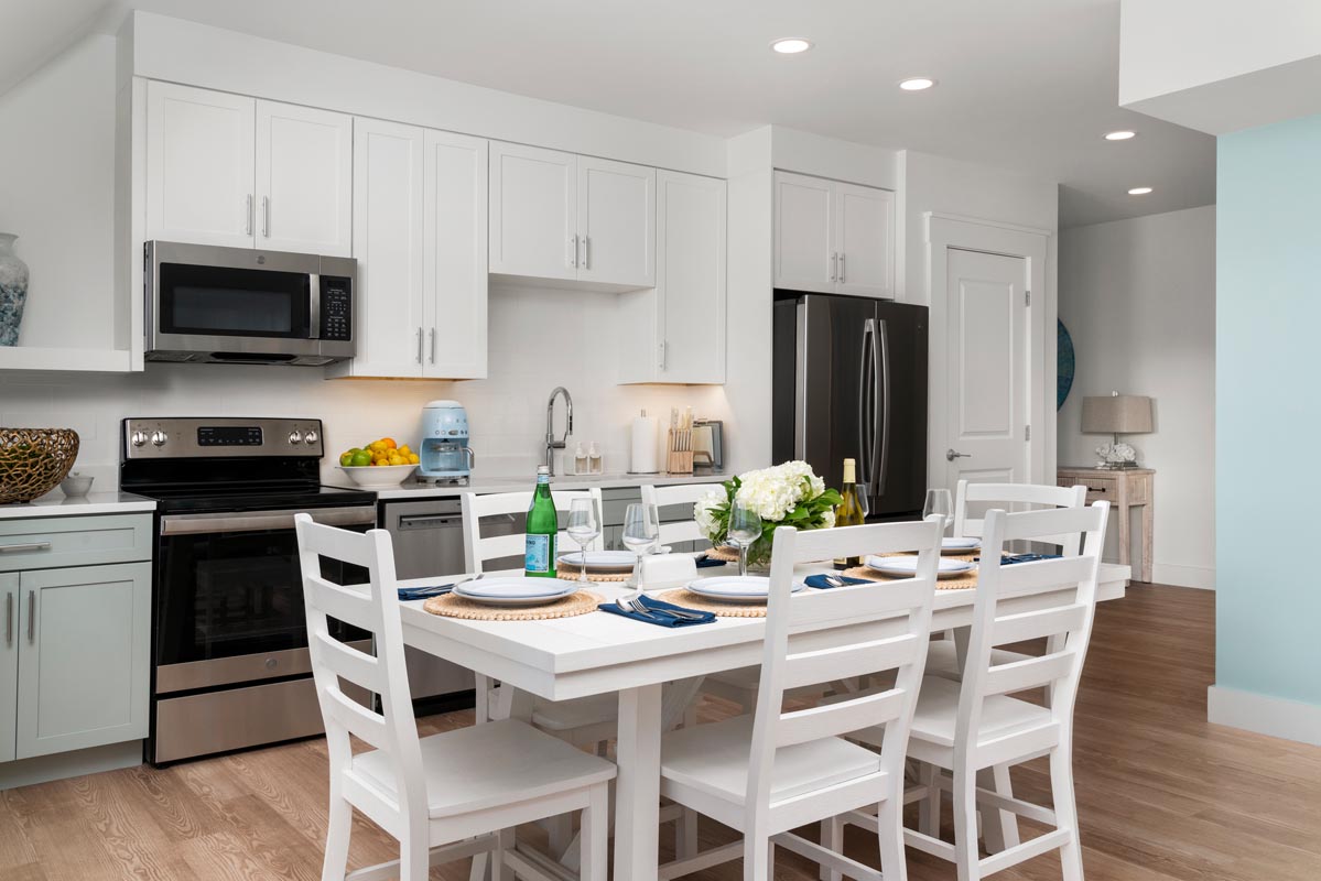 Kitchen with dining table that is set with plates, wine glasses and bottles of water