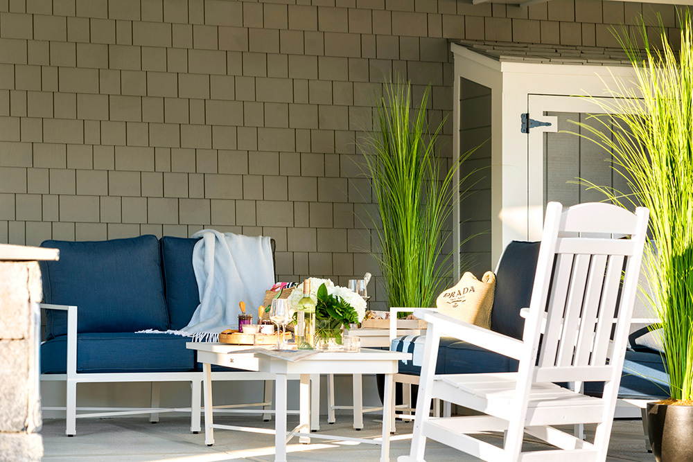 Cozy patio with a rocking chair and seating, featuring a coffee table set with wine and glasses