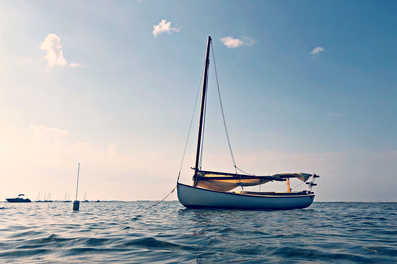 Sail boat tied to a booy on the water with the sunset in the background